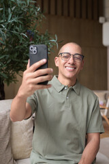 Latin bald man using smartphone in hotel lounge cafe business casual lifestyle and communication