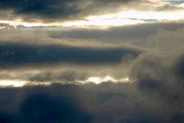 Dramatic evening sky with dark clouds at sunset. Silhouetted tree tops frame the moody scene, capturing the beauty of changing weather and fading daylight.