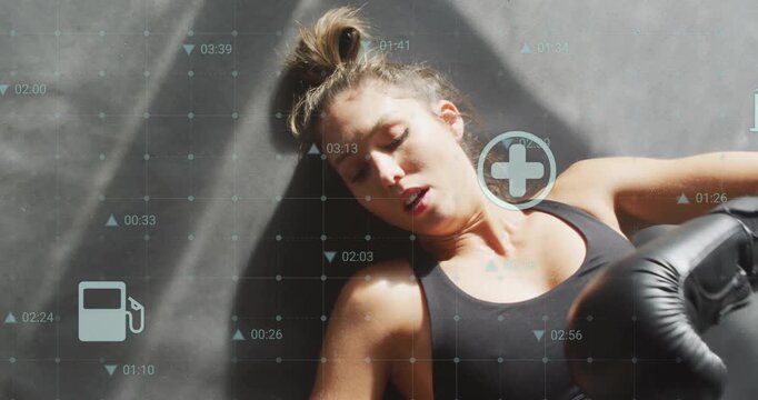 Woman panting on mat donning boxing glove while fitness icons for energy fuel tracking stamina