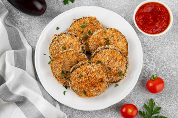 Baked garlic crispy eggplant with tomato sauce on a plate. Vegetarian food. Selective focus, top view.