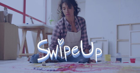 Painting female artist wearing apron applying vibrant paint onto canvas on studio floor, with jars