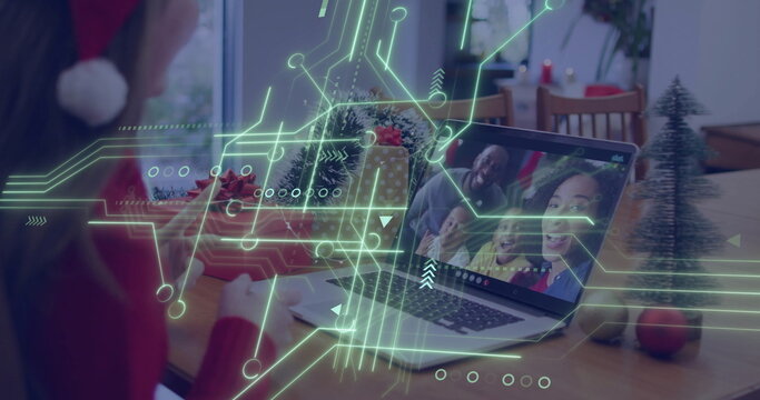 Leaning woman in red sweater and Santa hat using laptop at home dining table, copy space