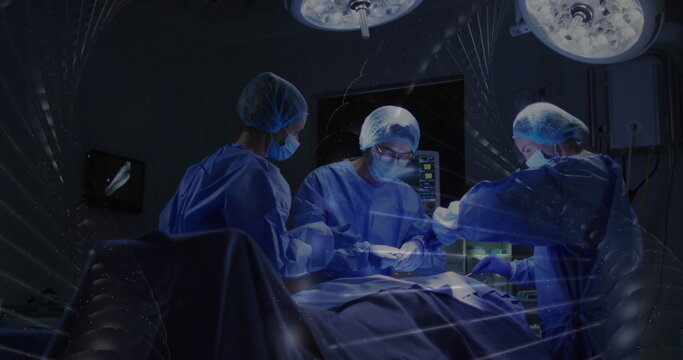 Performing surgery surgical team wearing gowns operating in OR, with lights and surgical table