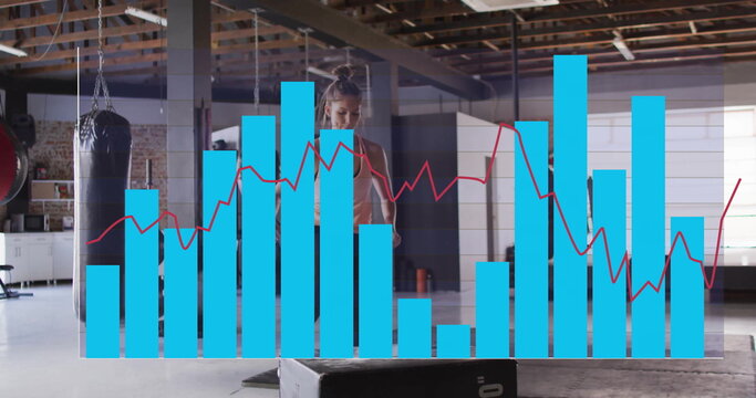 Jumping female athlete in sports bra and leggings performing box jump in gym with graph overlay