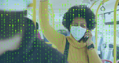 Masked commuter in yellow sweater gripping strap and calling on smartphone on bus, with data stream