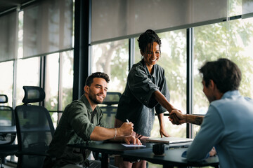 Handshake of happy young business woman and business man at office meeting