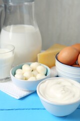 Different dairy products and eggs on light blue wooden table, closeup