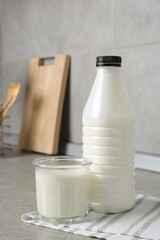 Dairy products. Fresh milk in glass and bottle on gray textured table indoors