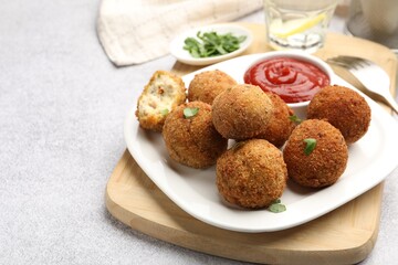 Delicious fried croquette balls with parsley and ketchup on grey textured table, closeup