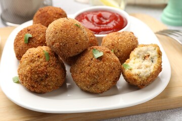 Delicious fried croquette balls with parsley and ketchup on grey textured table, closeup