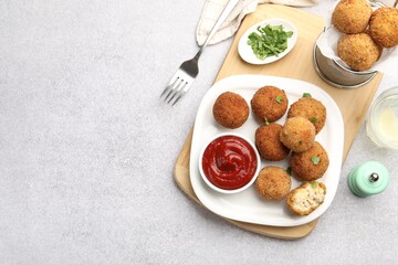 Delicious fried croquette balls with parsley and ketchup served on grey textured table, flat lay. Space for text