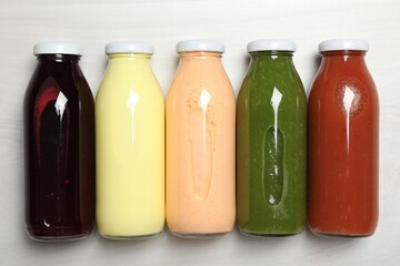 Superfood. Bottles with healthy drinks on light wooden table, flat lay