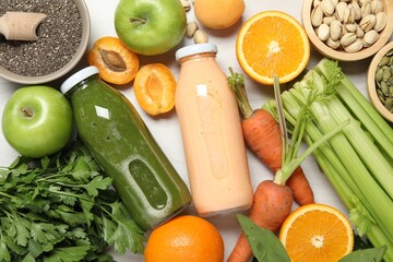 Superfood. Bottles with tasty smoothies and ingredients on light wooden table, flat lay