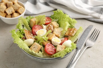 Delicious salad with croutons, chicken, quail eggs, tomato and cheese on grey table, closeup
