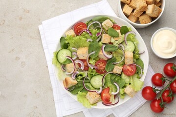 Delicious salad with croutons and vegetables served on light grey table, flat lay. Space for text