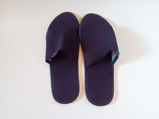 Pair of black disposable hotel guest slippers isolated on white background.