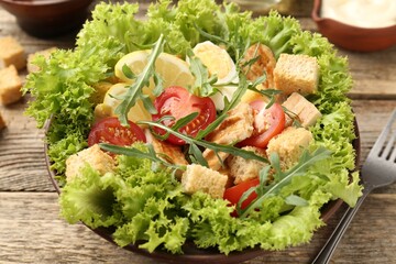 Delicious salad with croutons served on wooden table, closeup