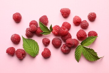 Tasty fresh ripe raspberries and leaves on pink background, flat lay