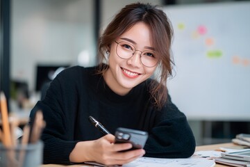 Obraz premium Smiling businesswoman using smartphone at modern office desk