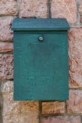 green post box on the wall of a building