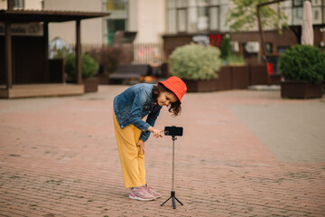 Girl teenager blogger influencer records videos from the blog on a smartphone outdoor.