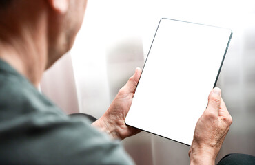 Senior man using digital tablet relaxing on couch at home. Close-up. Copy space. Selective focus.