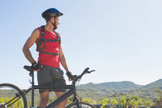 Fototapeta Mountain bike leaning against low stone barrier at scenic overlook, displaying red hydration pack