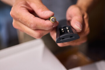 Fototapeta premium A hand holds a battery and remote control, vital for electronic device maintenance tasks