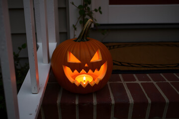 Obraz premium Glowing jack-o'-lantern with sharp teeth and angry eyes on brick step