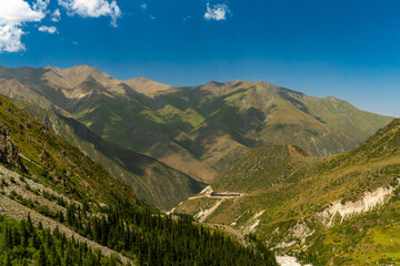 Ala-Archa, Mountain camp set in a vast alpine landscape, green slopes, rocky ridges, forested valleys, clear sky, perfect for outdoor trekking, climbing, hiking, backpacking, and alpine expeditions