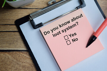Do you know about loot system write on sticky notes isolated on Wooden Table. A person is answering question concept