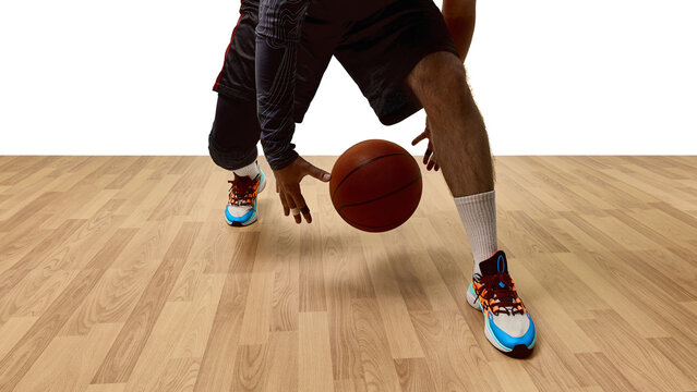 Close-up of basketball player dribbling ball on wooden court wearing bright sneakers. Concept of sports advertising, coaching, health recovery, digital ads, publishing.