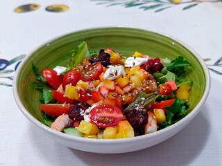 Salad with cherry tomatoes, shrimps, arugula, cucumber, feta cheese, mango, raspberries, sesame seeds.