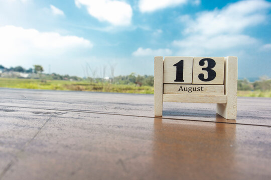 Wooden cube calendar for 13th August place on a table in a sunny day background