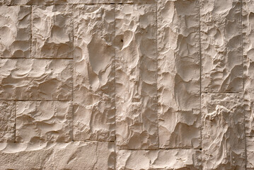 Yellowish stone or plaster surface, illuminated by natural sunlight, suitable for use as a background