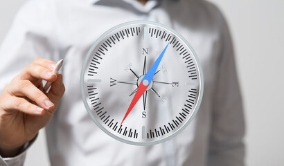 A businessman uses a digital compass, symbolizing strategic planning, navigation, and finding the right direction.