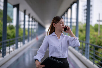Fototapeta premium Businesswoman walking and talking on phone in covered walkway