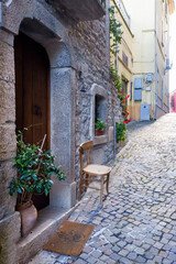 Naklejka premium wooden chair positioned in front of the door of a house in the old village of Nusco - Avellino