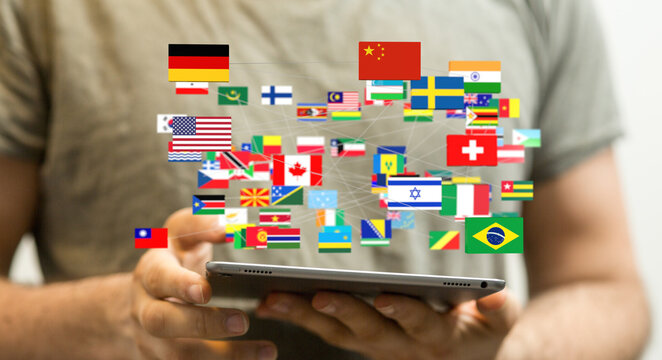 Stock photo of a person using a tablet to view a network of world flags, representing global communication and international relations. - Powered by Adobe