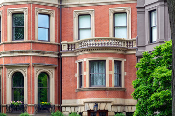 Historic Victorian townhouse with red-brick facade, bay window, and balcony in Boston, Massachusetts, USA