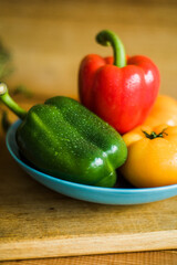 Fresh vegetables and berries in rustic kitchen. Bell peppers, sliced radish, and black currant on wooden background. Healthy organic food, seasonal produce, cooking ingredients and preparation scene.