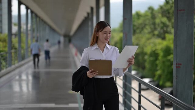 Businesswoman walking and reviewing documents on a skybridge