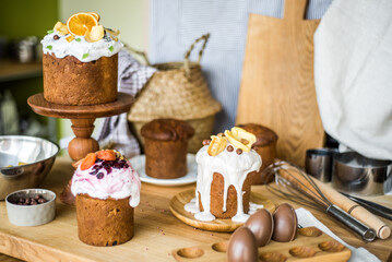 Traditional Easter cakes (kulich) with icing, dried fruits, and nuts on rustic background. Homemade...