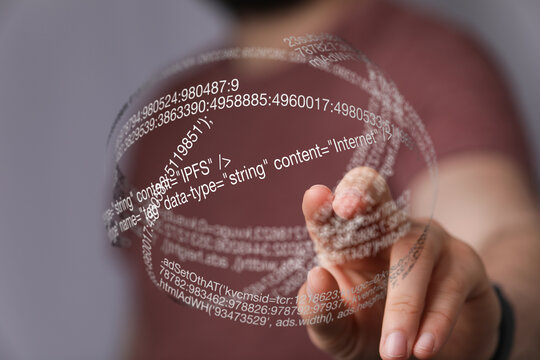 Hand interacting with a 3D holographic projection of computer code.