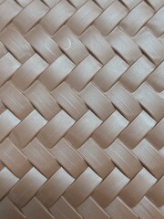 A flat weave pattern, resembling alternating strips stacked crisscrossing each other. A soft light brown or copper color, with a semi-glossy surface, resembling a brushed texture. It resembles a synth