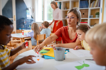 Preschool teacher interacting with a diverse group of children during an arts and crafts activity, fostering creativity and multicultural learning.