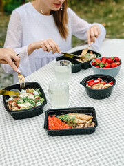 Healthy takeaway meals in lunch boxes with vegetables, fruits, and rice. Outdoor picnic, eating in car, casual food to-go, fitness meals, eco packaging, lifestyle food photography.