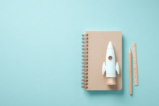 Creative workspace features notebook with rocket model and penci