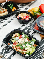 Healthy takeaway meals in lunch boxes with vegetables, fruits, and rice. Outdoor picnic, eating in car, casual food to-go, fitness meals, eco packaging, lifestyle food photography.