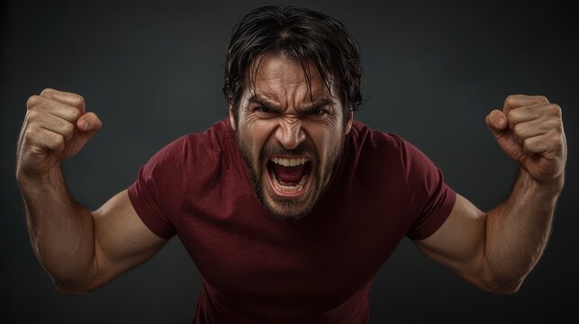 Man with furrowed brow and open mouth shouts aggressively fists clenched